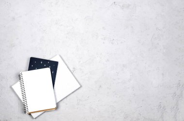 Gri çalışma masası, boş defterler, malzemeler ve bardaklar. Metnin için en üstte boşluk var. Düz yatıyordu. Asgari tarz ev ofisi ya da Modern Serbest İşyeri.