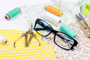Dikiş seti kumaş, iplik makarası, makas ve gözlük.