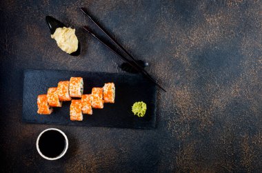 Sos, yemek çubuğu, zencefil ve wasabi ile taştan tabakta suşi ruloları.