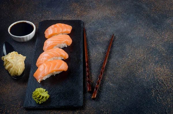 酱油，生姜，芥末，黑石板上有鲑鱼味的黑鬼寿司 — 图库照片
