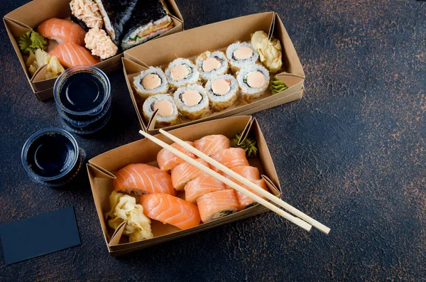 Rolos de sushi saborosos em caixas de papel kraft descartáveis, molhos, pauzinhos. Sushi para levar ou entrega — Fotografia de Stock