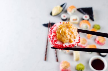 Yemek çubuklarını kapatın. Masanın üzerinde suşi, soya sosu, zencefil ve wasabi ile porsiyon suşi alın. Suşi menüsü. Japon yemeği servisi. Moda melezi gıdaları.