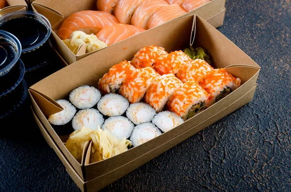 Smaczne Bułki Sushi Jednorazowych Pudełkach Papieru Kraft Sosy Ciemnym Stole — Zdjęcie stockowe