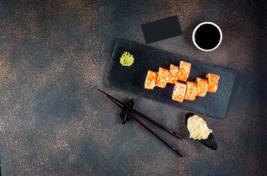 Lezzetli California dürümleri ve Maki tabakta soslar, yemek çubukları, zencefil ve wasabi. Asya menüsü. Japon yemeği servisi. Çeşitli suşiler.