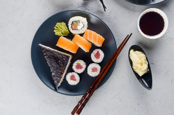 将不同的寿司卷放在盘子里 芥末和筷子放在灰色混凝土桌子上 亚洲餐馆菜单 日本食品递送服务 模板模型 文字位置 — 图库照片