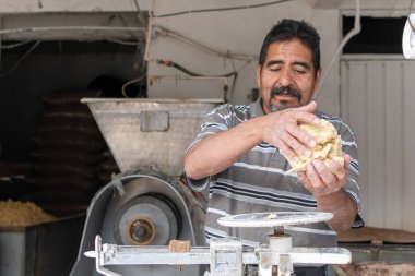 Nixtamal değirmeninde hamur satan bir adam. Hamuru tartmak için sarkaç kullanılıyor..