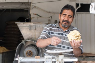 Nixtamal değirmeninde hamur satan bir adam. Hamuru tartmak için sarkaç kullanılıyor..