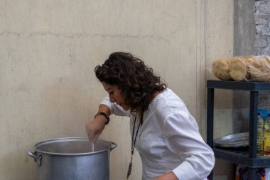 Yaşlı bir kadın büyük bir tencerede pozole hazırlıyor.