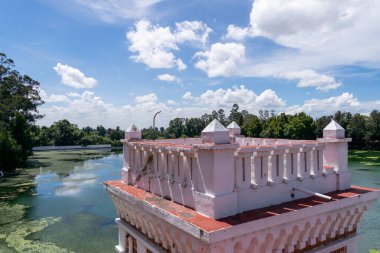 Göle bakan pembe kale kulesi ve arka planda bir orman.