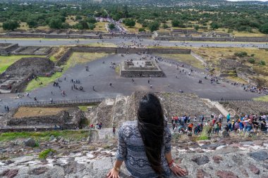 Genç kız Teotihuacan harabelerini güneş piramidinin tepesinden izliyor.