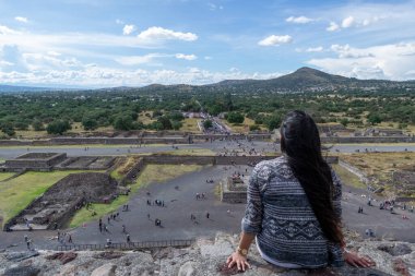 Genç kız Teotihuacan harabelerini güneş piramidinin tepesinden izliyor.