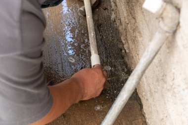 Kendi evinin tüpünü tamir eden bir adamın elleri.