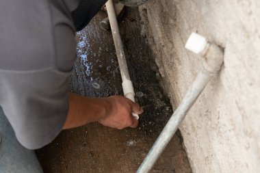 Kendi evinin tüpünü tamir eden bir adamın elleri.