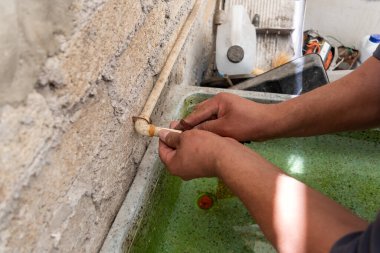 Kendi evinin tüpünü tamir eden bir adamın elleri.