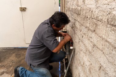 Kendi evinin bozuk tüpünü tamir eden yaşlı bir adam.