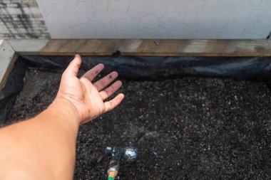 Bir yatağı sulamak için hortum taşıyan bir el.