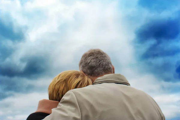 Achteraanzicht aan een bejaarde echtpaar. de vrouw stak haar hoofd op de schouder van de man. tegen een achtergrond van een diep blauwe hemel. — Stockfoto