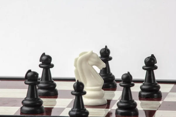 Šachy white horse, obklopen černými pěšci. koncepce boje. Izolované na bílém pozadí. — Stock fotografie
