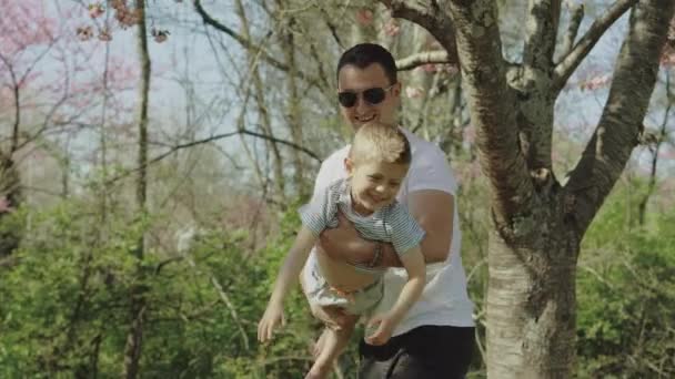 Kleiner Junge, der an einem sonnigen Tag mit seinem Vater in einem Park spielt und Spaß hat — Stockvideo