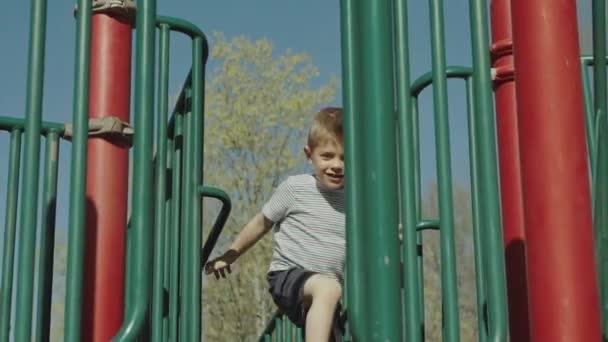 Маленький мальчик на детской площадке летом — стоковое видео