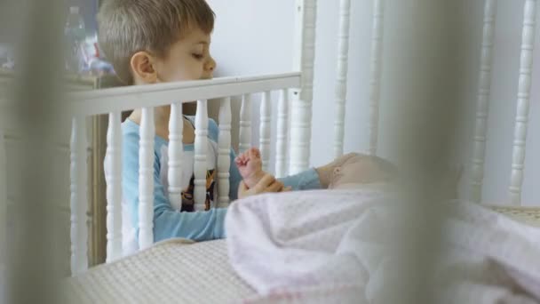 Söt liten bebis ligger på sängen hemma med bror 4k — Stockvideo