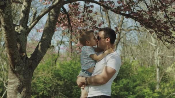 Маленький мальчик играет и веселится со своим отцом в парке в солнечный день — стоковое видео