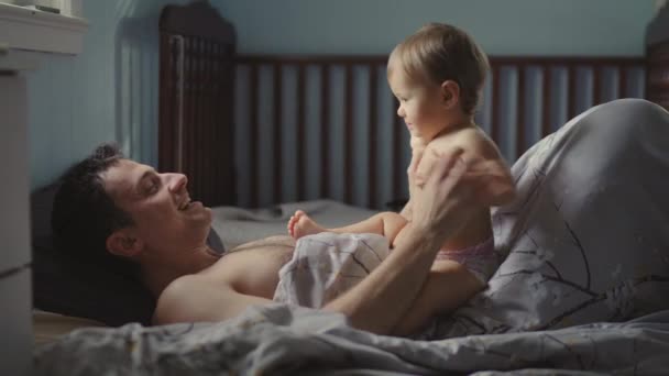 Bonito jovem pai está brincando com seu bebê bonito menina e sorrindo — Vídeo de Stock