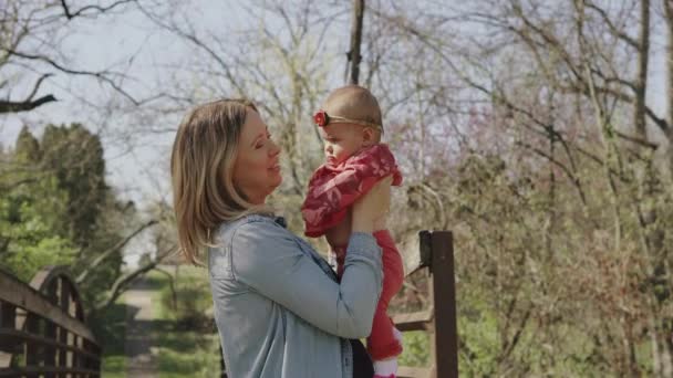 Madre jugando y divirtiéndose con su pequeña niña, parque de primavera. Feliz mamá y el niño en el parque en un día soleado — Vídeo de stock