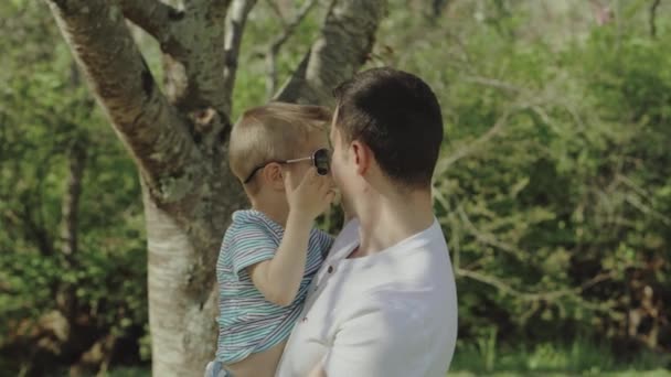 Menino brincando e se divertindo com seu pai em um parque em um dia ensolarado — Vídeo de Stock