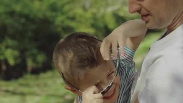 Kleiner Junge, der an einem sonnigen Tag mit seinem Vater in einem Park spielt und Spaß hat — Stockvideo