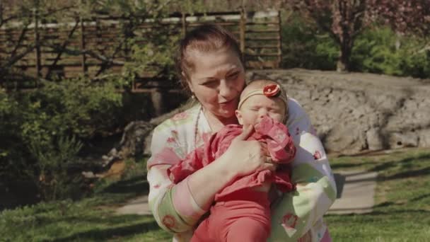 Baby girl on hands of her grandmother outdoor. — Stockvideo