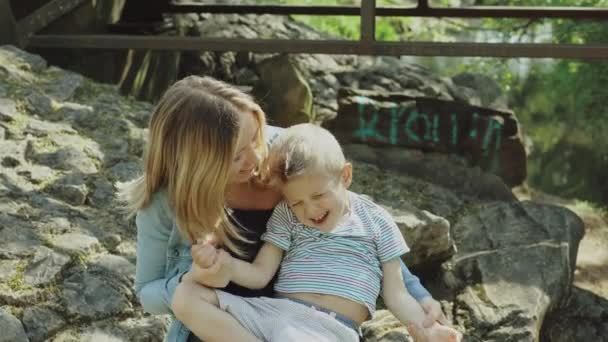 Piękna młoda mama i wesoły uroczy blondyn bawią się, dobrze się bawią. Kobieta kocha swojego syna. Piękna młoda mama i wesoły uroczy blond chłopiec bawią się w parku — Wideo stockowe