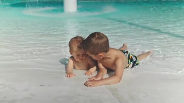 Feliz niño y niña en la piscina jugando — Vídeos de Stock