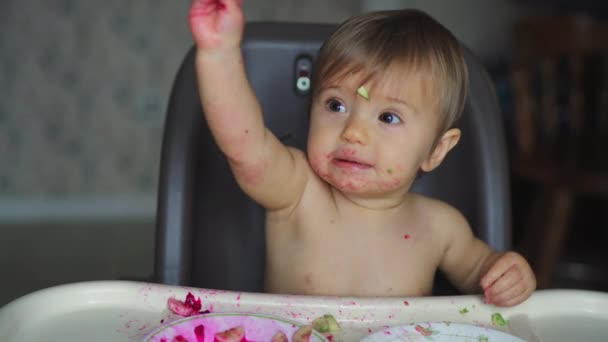 Kislány eszik gyümölcsöt és zöldséget ül fehér etetőszékben — Stock videók