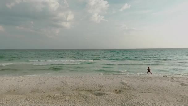 Eine Frau im Bikini läuft von oben am Strand entlang. Luftaufnahme einer schlanken Frau in der Nähe des Ozeans im Urlaub — Stockvideo