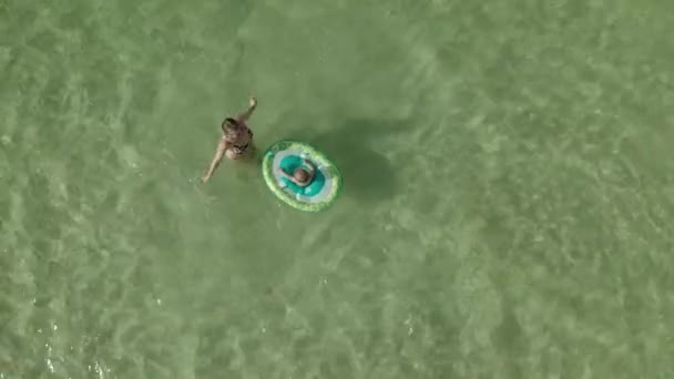 Ung kvinna med en liten flicka simmar tillsammans i havet. Vy från ovan av barnet flicka med simning cirkel flyter tillsammans med mamma — Stockvideo