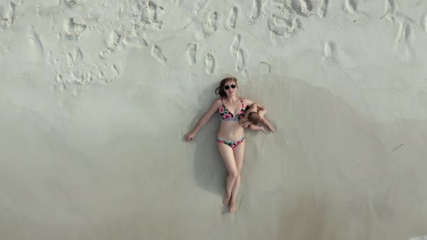 彼女の赤ちゃんの女の子とビーチで横たわっ女性の空中ビュー — ストック動画
