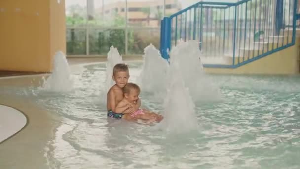 A kisfiú és a kislány jól érzik magukat a medencében. Testvér és a húga jól érzik magukat a medencében. — Stock videók