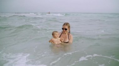 Mutlu genç anne ve küçük kızı Panama City Plajı 'ndaki okyanus suyunda eğleniyorlar.