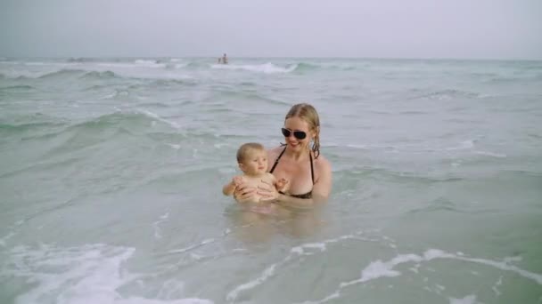 Щаслива молода мати з маленькою дівчинкою бавляться у воді океану на пляжі Панама - Уса. — стокове відео