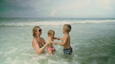 Genç ve mutlu bir kadın, Panama City Plajı 'ndaki okyanus suyunda çocuklarıyla eğleniyor.