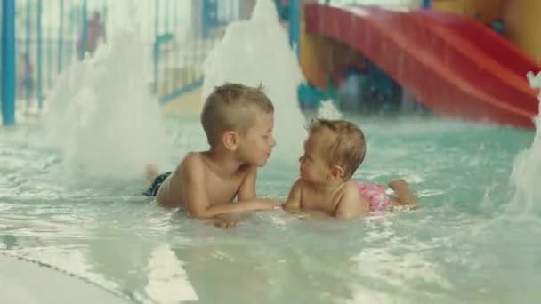 Petit garçon et petite fille s'amusent dans la piscine. Frère et sa sœur s'amusent dans la piscine — Video