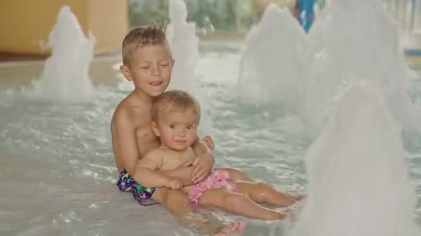 Liten pojke och liten flicka har roligt i poolen. Broder och hans syster har kul i poolen — Stockvideo