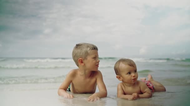 Pequena menina engraçada e seu irmão mais novo deitado na praia. Panamá City Beach EUA — Vídeo de Stock