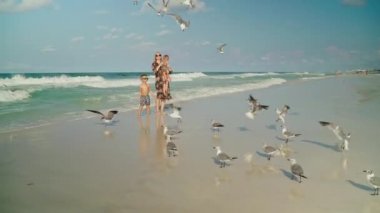 Genç anne ve küçük oğlu, yaz tatili için Florida sahilinde martı besliyor.
