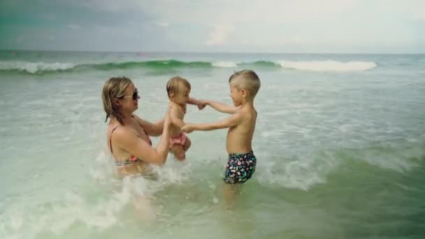 Feliz joven divirtiéndose con sus pequeños niños en el agua del océano en Panama City Beach USA — Vídeos de Stock