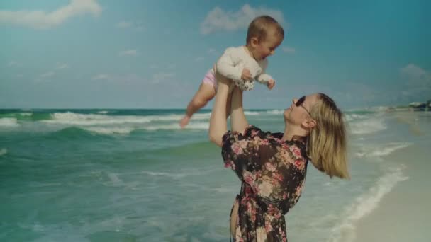 Feliz madre joven y su bebé divirtiéndose en la playa de la Ciudad de Panamá. Gran cielo y olas en el fondo USA — Vídeos de Stock