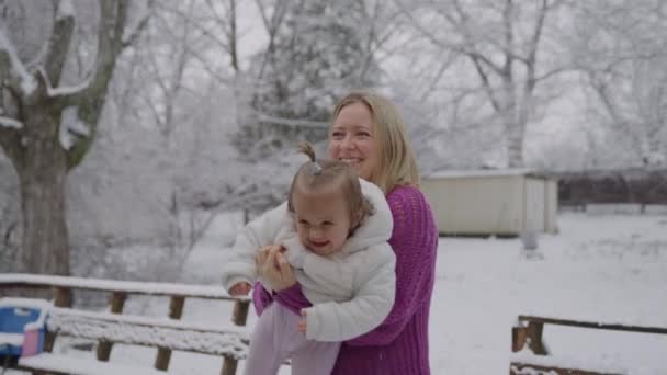 Joven mujer rubia con su linda niña disfrutando en el parque de nieve — Vídeo de stock