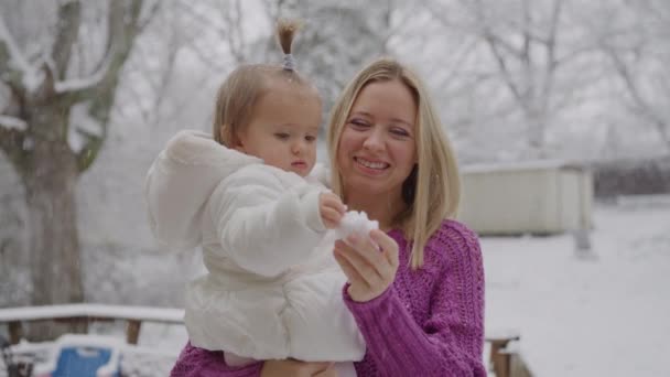 Молодая блондинка со своей милой маленькой девочкой наслаждается в снежном парке — стоковое видео
