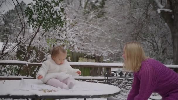 Joven mujer rubia con su linda niña disfrutando en el parque de nieve — Vídeos de Stock